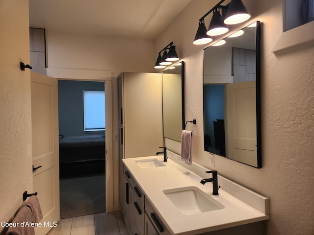 bathroom with a sink, connected bathroom, double vanity, and a textured wall