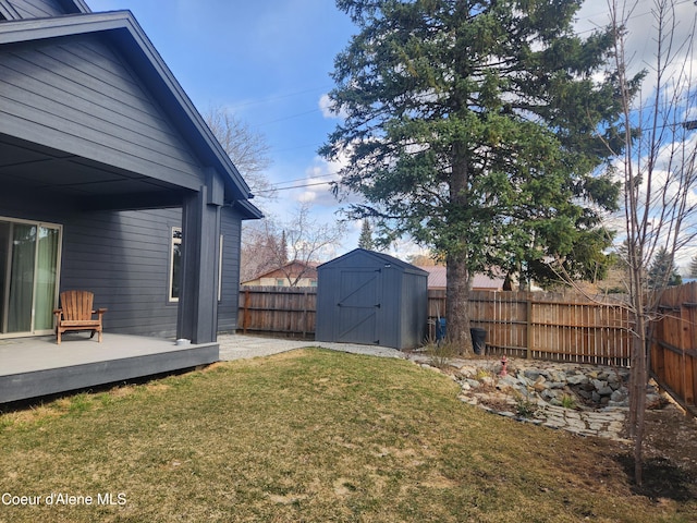 view of yard with a deck, an outdoor structure, a fenced backyard, and a shed