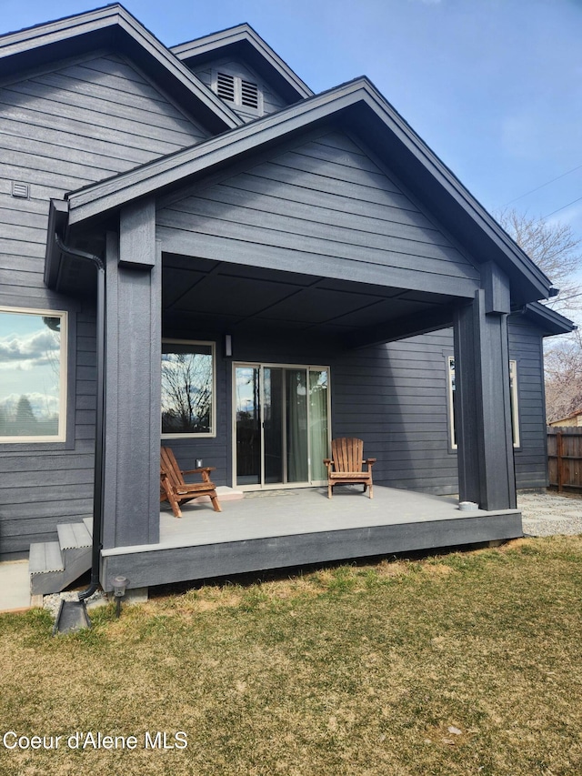 back of property featuring a yard, a wooden deck, and fence