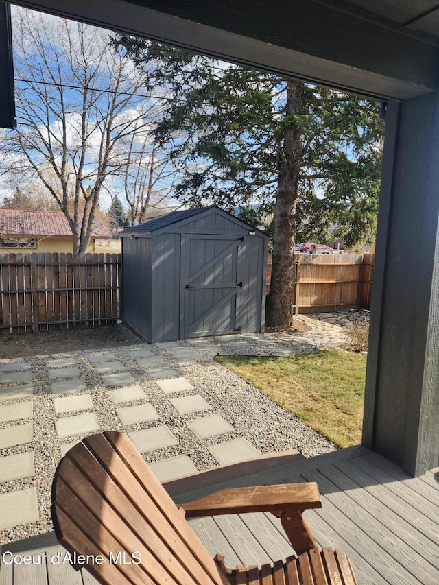 wooden terrace with an outbuilding, a storage shed, and a fenced backyard