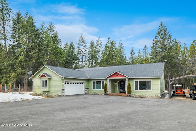 view of front of house featuring an attached garage, driveway, roof with shingles, and fence