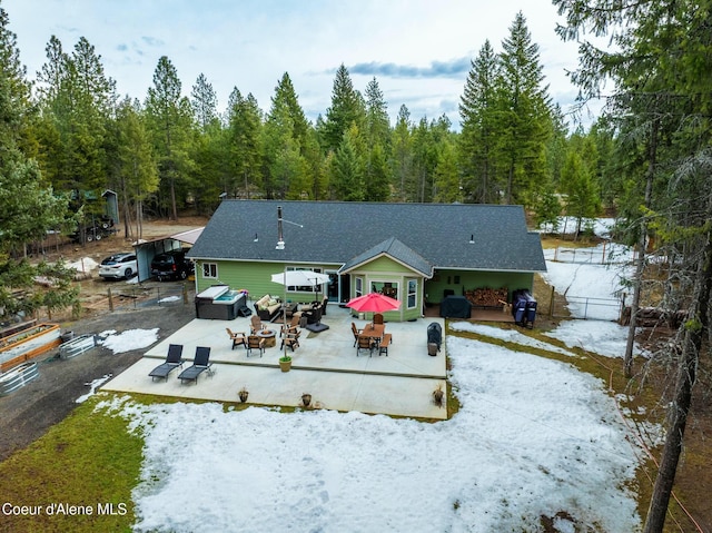 back of property with a patio area, driveway, an outdoor fire pit, and a view of trees