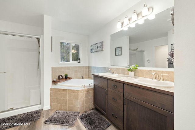 bathroom featuring a sink, a stall shower, double vanity, and a bath