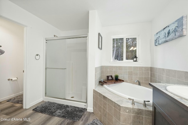 full bath featuring wood finished floors, a stall shower, vanity, and a bath