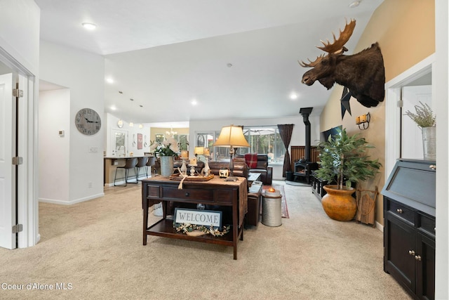 living area with baseboards, light colored carpet, vaulted ceiling, recessed lighting, and a wood stove