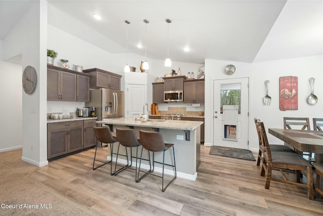 kitchen featuring a breakfast bar area, light wood finished floors, appliances with stainless steel finishes, and a sink