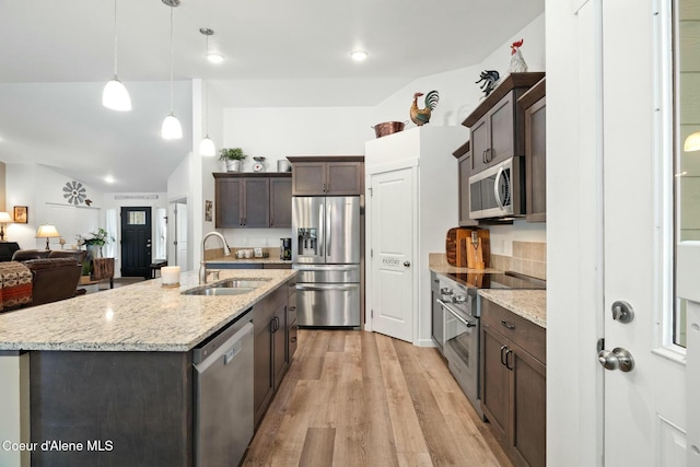 kitchen with light wood-type flooring, a sink, stainless steel appliances, light stone countertops, and dark brown cabinets