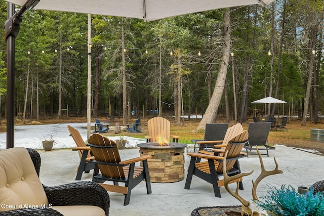 view of patio with a view of trees and an outdoor fire pit