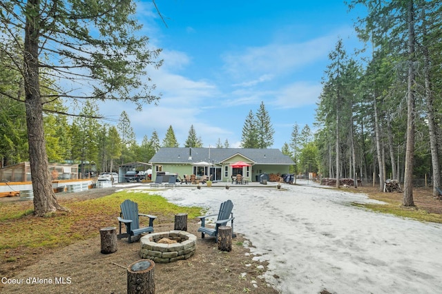 rear view of house featuring a patio, a detached carport, driveway, and an outdoor fire pit