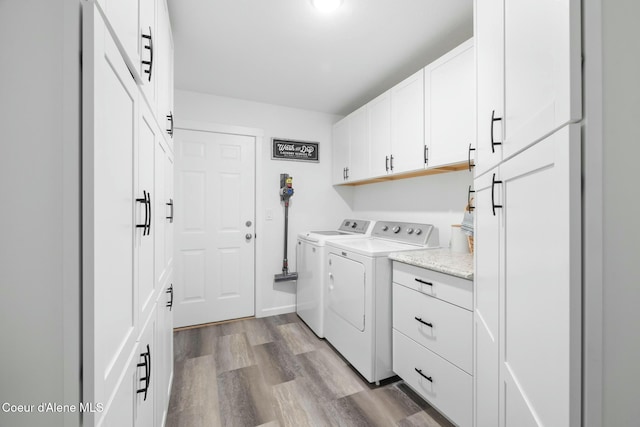 laundry area with washer and dryer, wood finished floors, and cabinet space