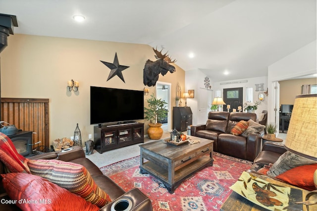 living area with carpet flooring, lofted ceiling, and a wood stove