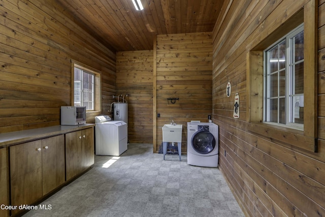 washroom with washing machine and clothes dryer, wooden walls, light floors, wood ceiling, and cabinet space