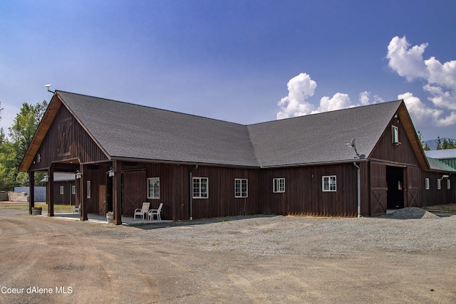 view of home's exterior with a detached garage, a barn, an outdoor structure, and a shingled roof