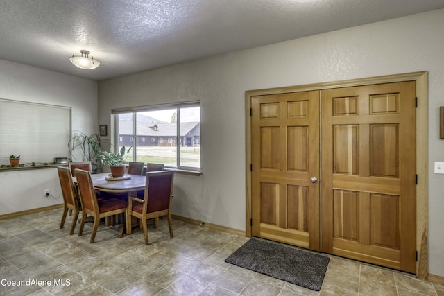 dining space with a textured wall, baseboards, and a textured ceiling