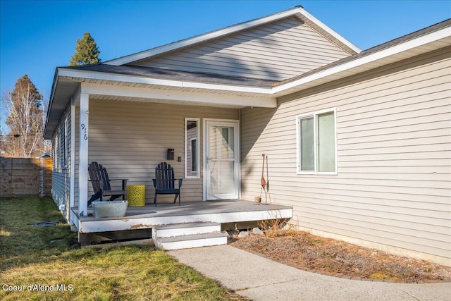 view of exterior entry with a porch and fence