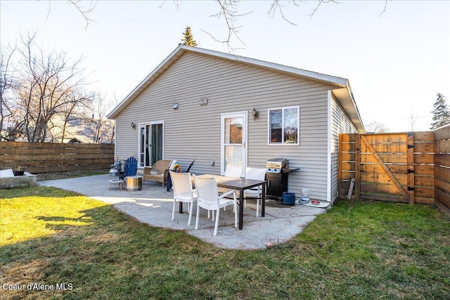 back of house with a fenced backyard, a lawn, a patio, and a gate