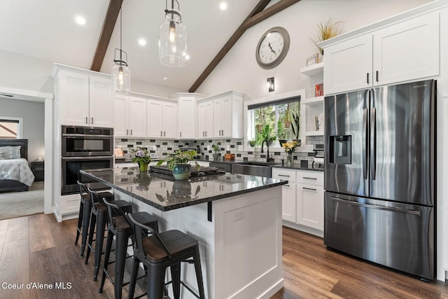 kitchen with white cabinets, vaulted ceiling with beams, appliances with stainless steel finishes, and a sink