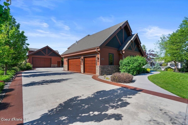 view of property exterior featuring stone siding, a lawn, and driveway