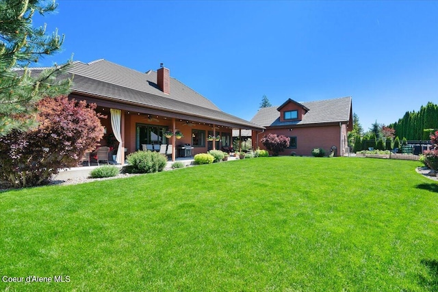 back of property featuring ceiling fan, fence, a chimney, a yard, and a patio