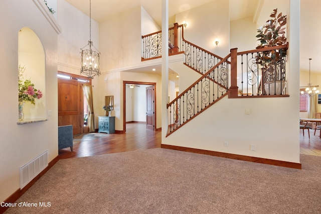 foyer with visible vents, carpet floors, an inviting chandelier, and stairway