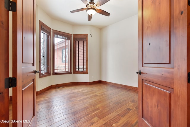 unfurnished room with a ceiling fan, baseboards, and light wood finished floors