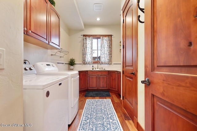 washroom featuring recessed lighting, wood finished floors, cabinet space, independent washer and dryer, and a sink