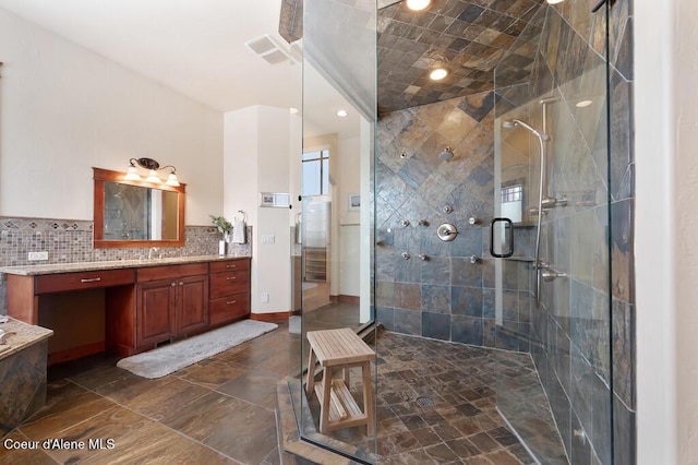 bathroom featuring visible vents, backsplash, a shower stall, baseboards, and vanity