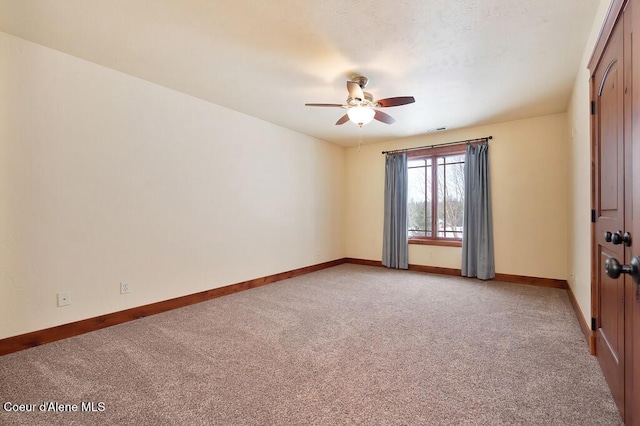 empty room featuring baseboards, light carpet, and ceiling fan