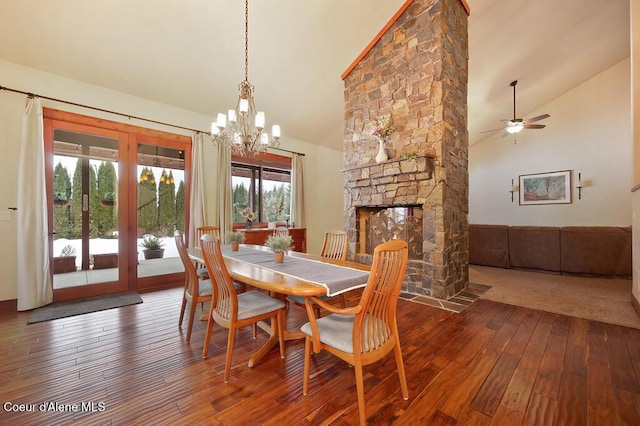 dining area featuring a stone fireplace, hardwood / wood-style flooring, a ceiling fan, and high vaulted ceiling