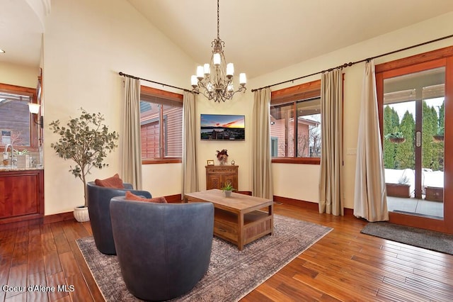 living area with dark wood finished floors, an inviting chandelier, baseboards, and high vaulted ceiling