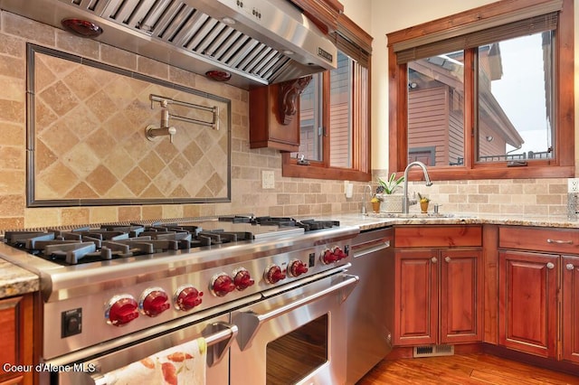 kitchen with tasteful backsplash, visible vents, custom range hood, stainless steel appliances, and a sink