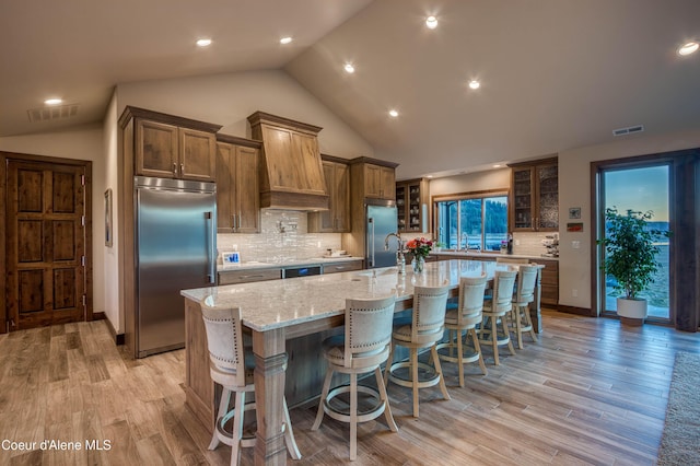 kitchen with visible vents, a spacious island, built in fridge, and light wood finished floors