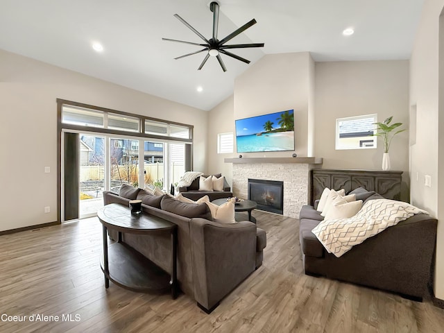 living area featuring wood finished floors, baseboards, high vaulted ceiling, a fireplace, and ceiling fan