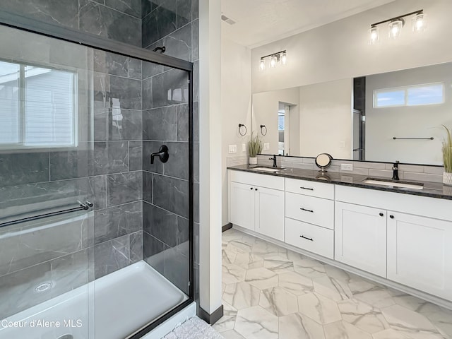 bathroom with marble finish floor, a stall shower, and a sink