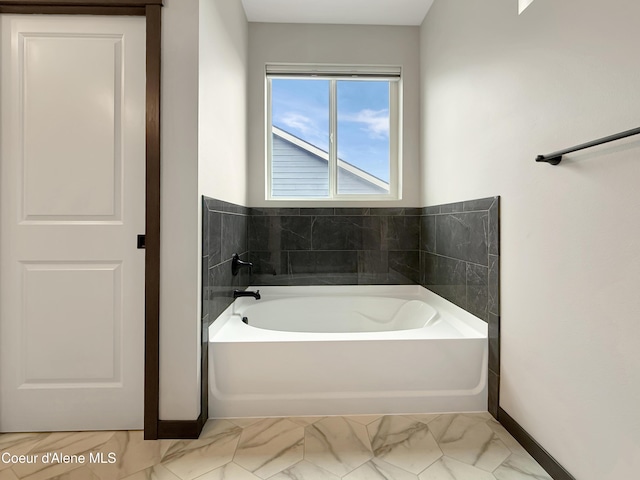 full bath with marble finish floor, baseboards, and a garden tub