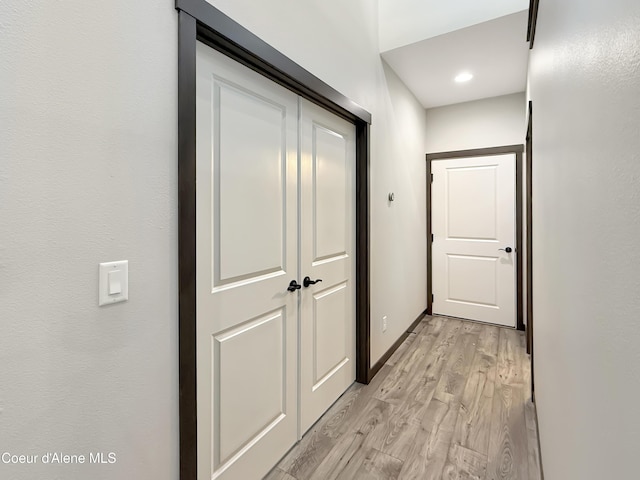 hall featuring light wood-style flooring and baseboards