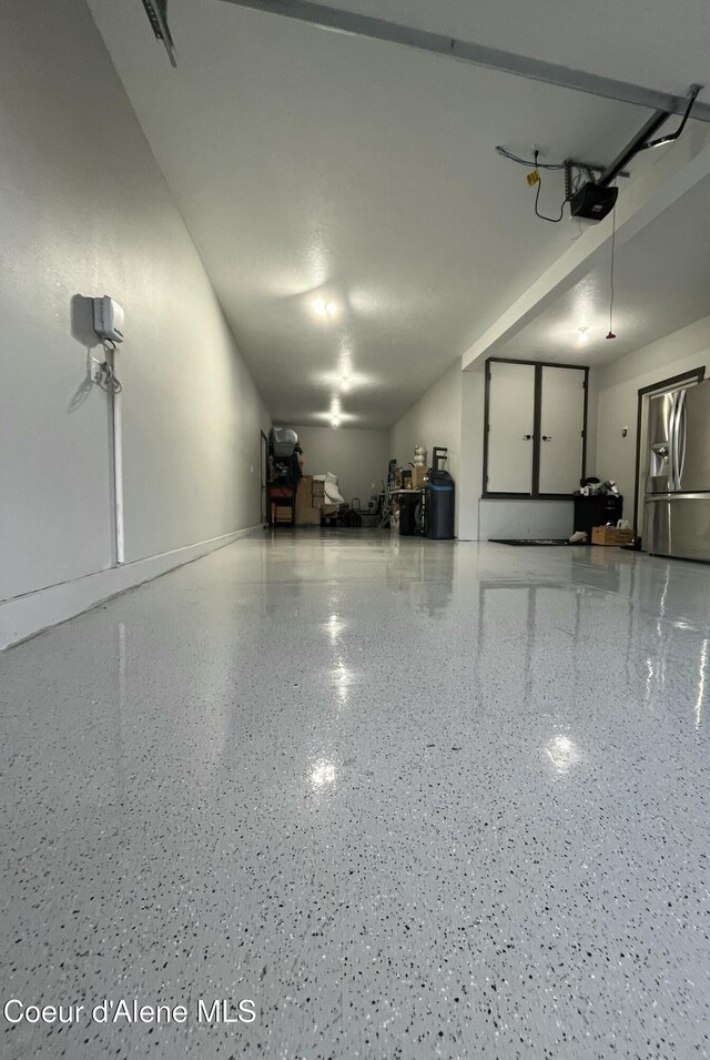 garage featuring stainless steel fridge and a garage door opener