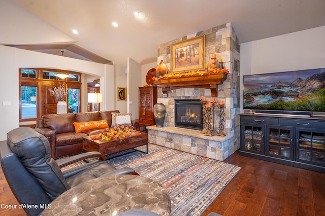 living area with recessed lighting, wood-type flooring, and a stone fireplace