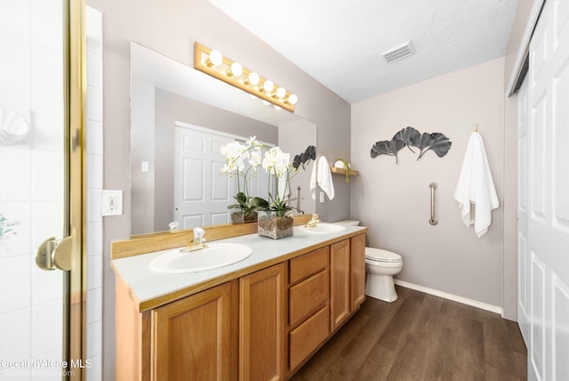 full bath with a sink, visible vents, wood finished floors, and double vanity