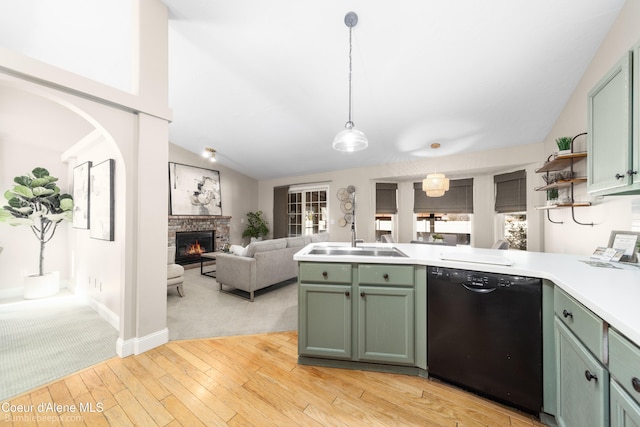 kitchen with a sink, a glass covered fireplace, green cabinetry, lofted ceiling, and dishwasher