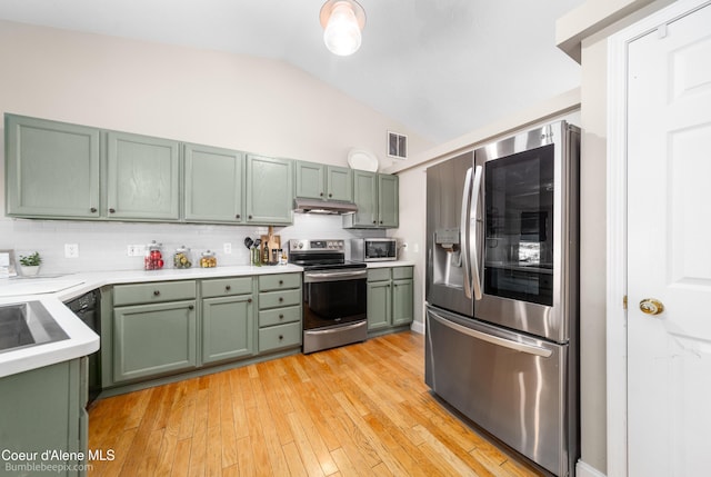 kitchen with visible vents, green cabinetry, lofted ceiling, under cabinet range hood, and appliances with stainless steel finishes