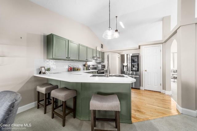 kitchen with green cabinets, a breakfast bar, lofted ceiling, a peninsula, and stainless steel refrigerator with ice dispenser