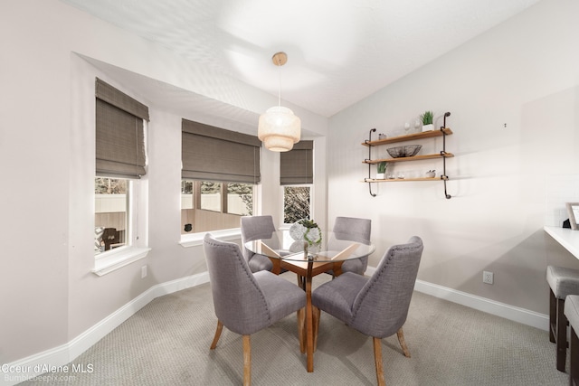 carpeted dining room featuring baseboards and lofted ceiling