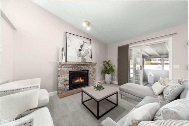 living area featuring a brick fireplace, baseboards, carpet, and vaulted ceiling