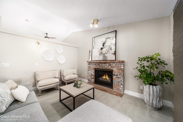 carpeted living room featuring baseboards, lofted ceiling, ceiling fan, and a fireplace