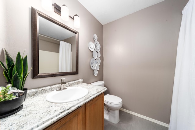 bathroom with toilet, vanity, and baseboards