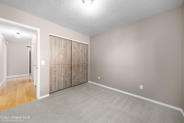 unfurnished bedroom featuring a barn door, baseboards, a textured ceiling, and carpet floors