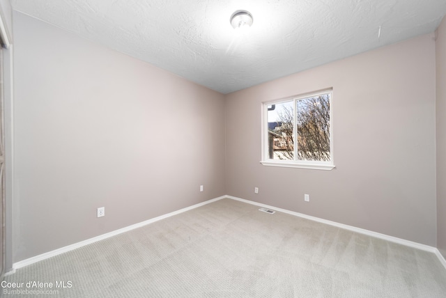 empty room featuring visible vents, baseboards, and light colored carpet