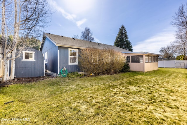 back of property with fence, a yard, roof with shingles, an outdoor structure, and a sunroom