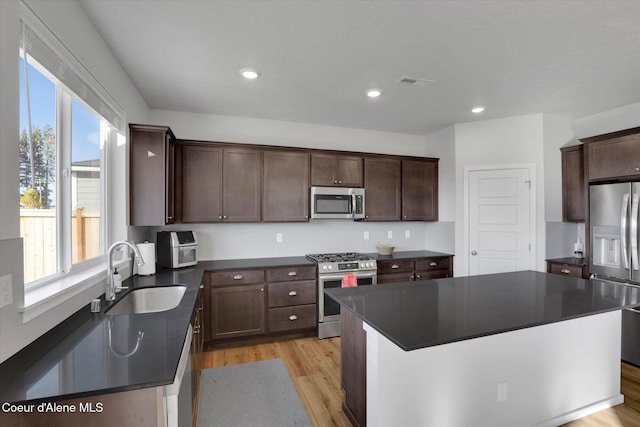 kitchen featuring visible vents, a sink, dark countertops, appliances with stainless steel finishes, and light wood finished floors